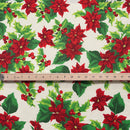 A repeating pattern of vibrant red poinsettias and green holly leaves with small red berries on a crisp white background. A ruler is placed across the center to show the scale of the print.