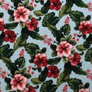 Hibiscus and Plumeria floral pattern on a light blue background with green Monstera and banana leaves.