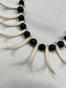 A traditional Samoan Ula Nifo lei made from a curved arrangement of pointed white shells interspersed with polished dark brown beads.