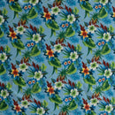Tropical floral pattern featuring clusters of white, orange, and red hibiscus flowers with green leaves on a vibrant light blue background.